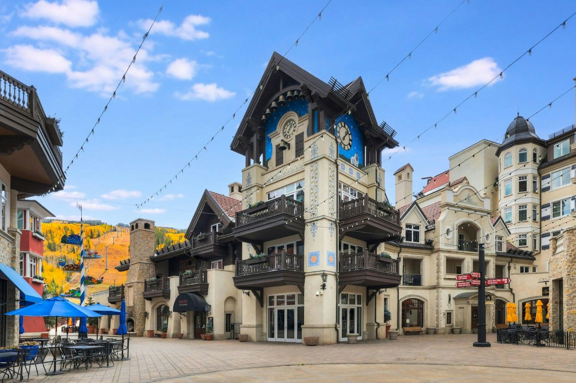 Scenic view of a town square with a clock tower, showcasing nearby shops and public seating areas.