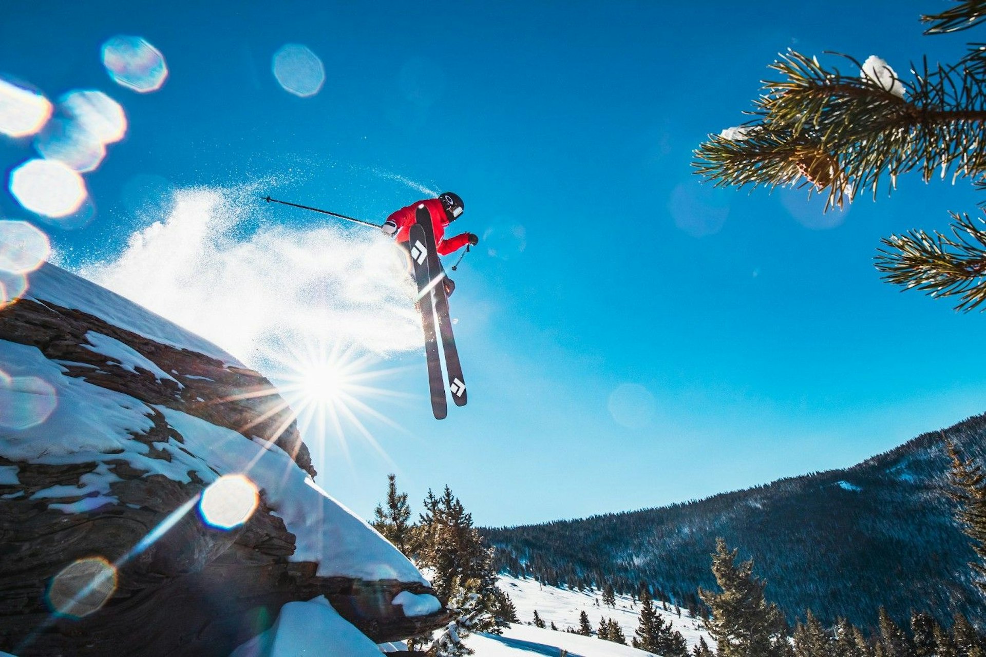 A skier performs a jump in mid-air above a snowy slope, showcasing skill and excitement in winter sports.
