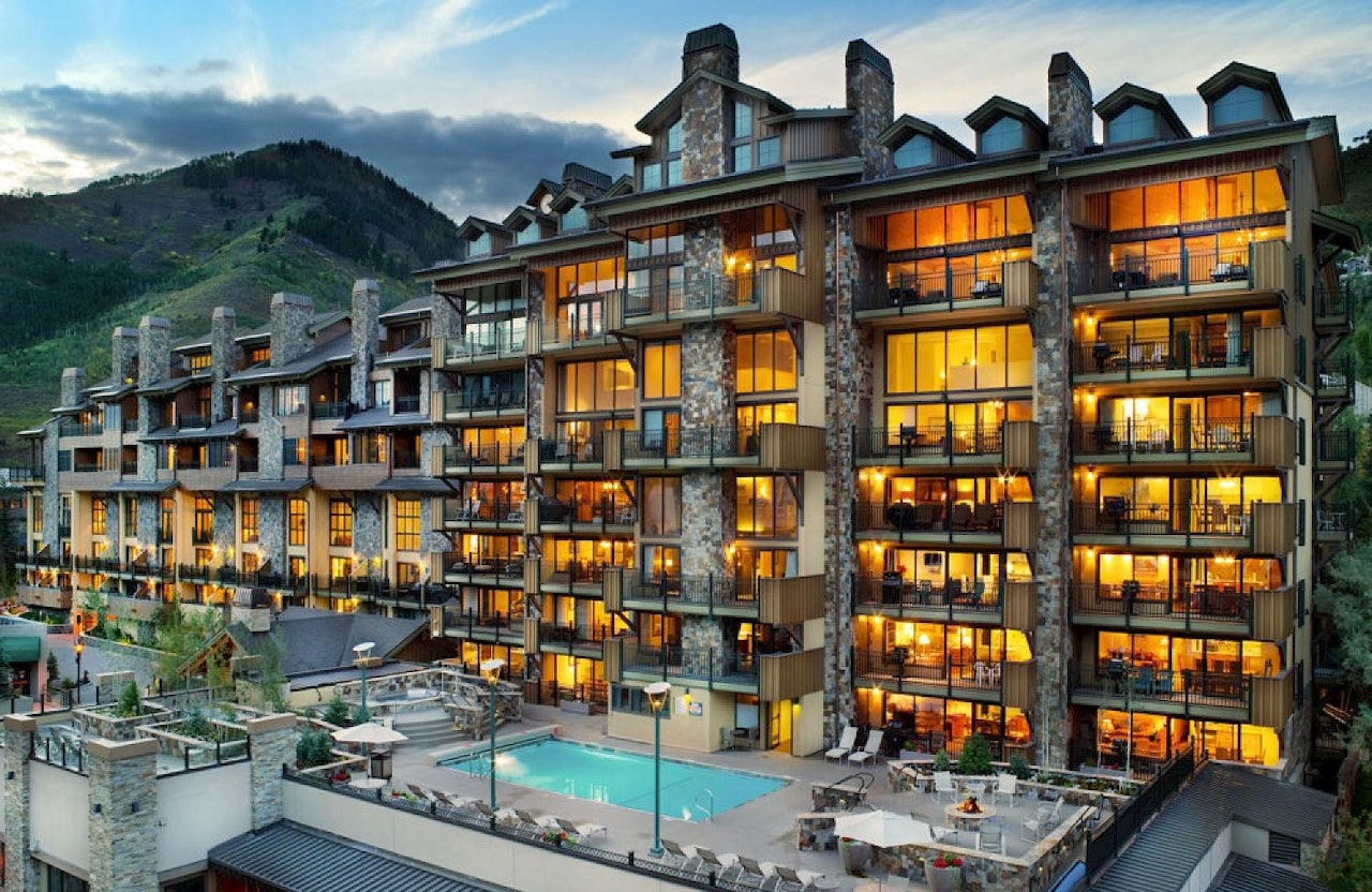 Night view of a resort featuring a pool with mountains illuminated in the background.
