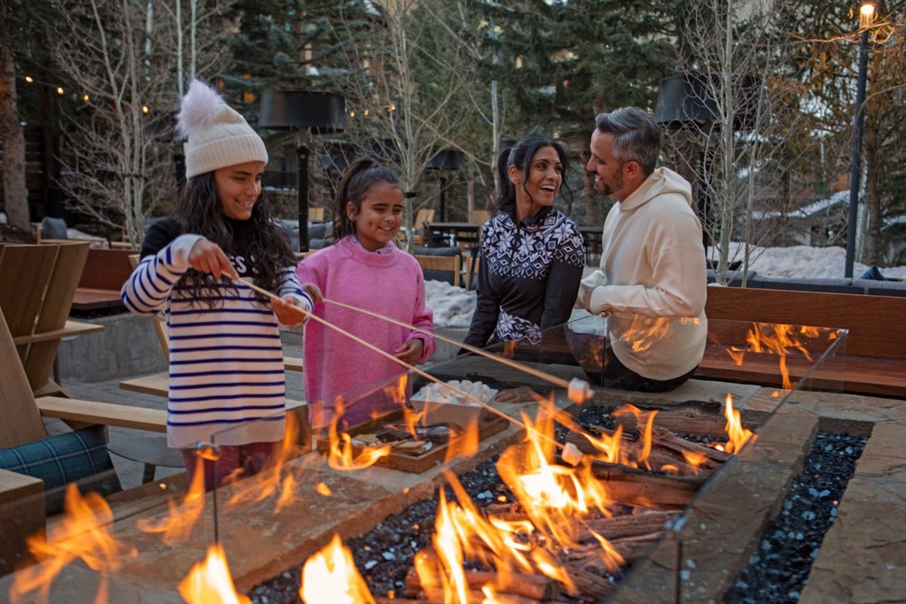 A family gathered around a bonfire at the lodge in Breckenridge, enjoying warmth and togetherness under the night sky.