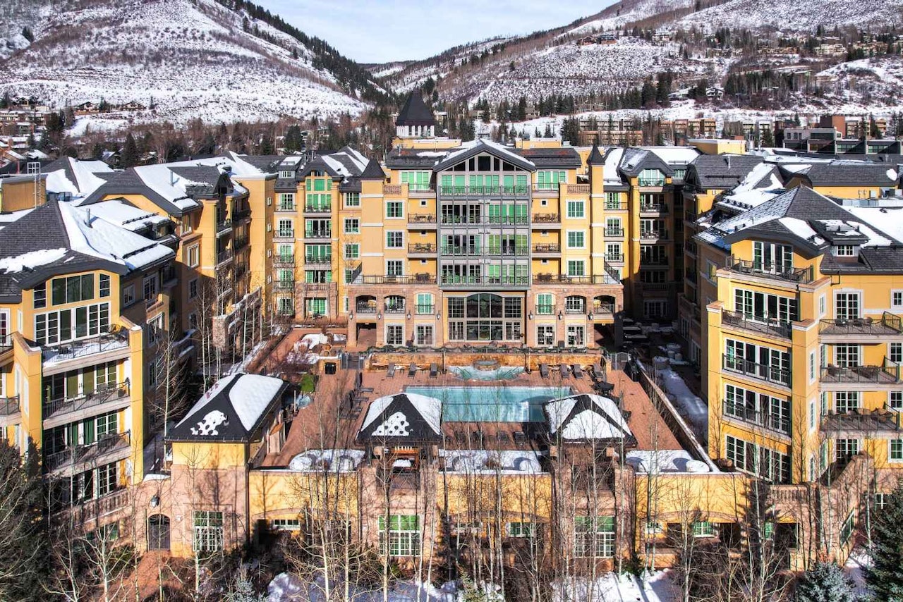 A snow-covered resort nestled at the base of a mountain, surrounded by a serene winter landscape.