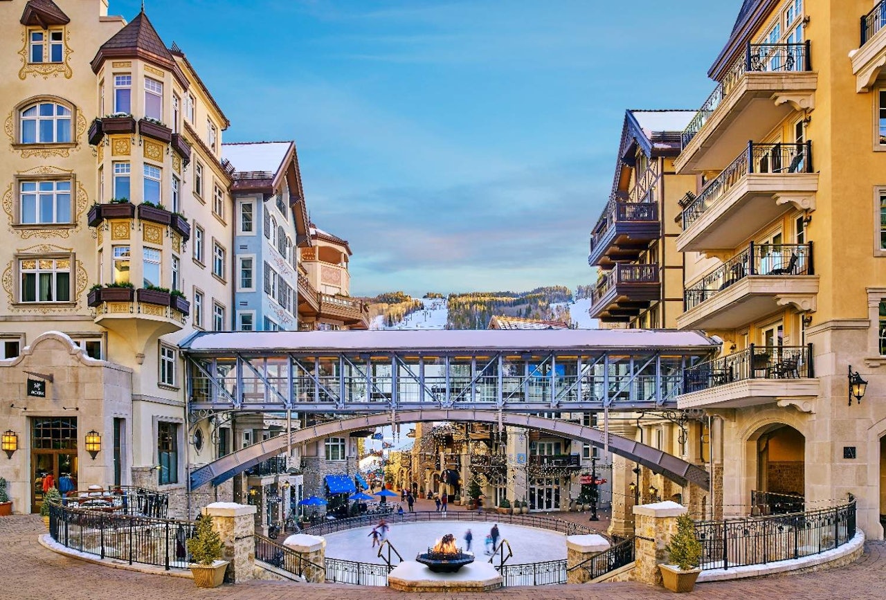 A bridge crosses a city street, surrounded by people walking and engaging in the lively urban atmosphere.