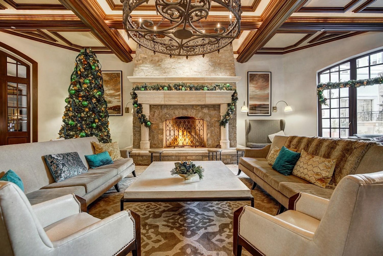 A cozy living room featuring a decorated Christmas tree beside a warm fireplace, creating a festive atmosphere.
