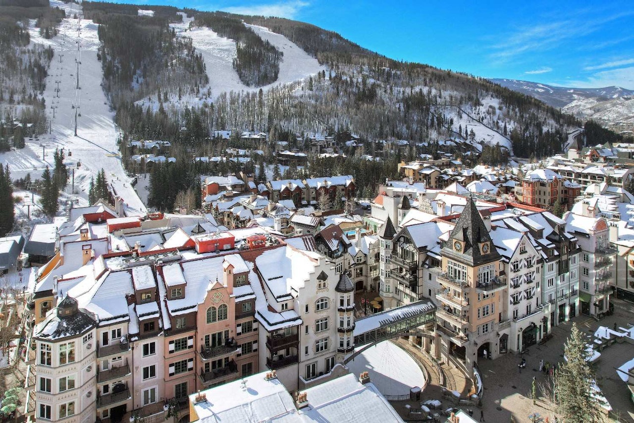 Aerial view of a ski resort showcasing slopes, lifts, and surrounding snow-covered mountains.