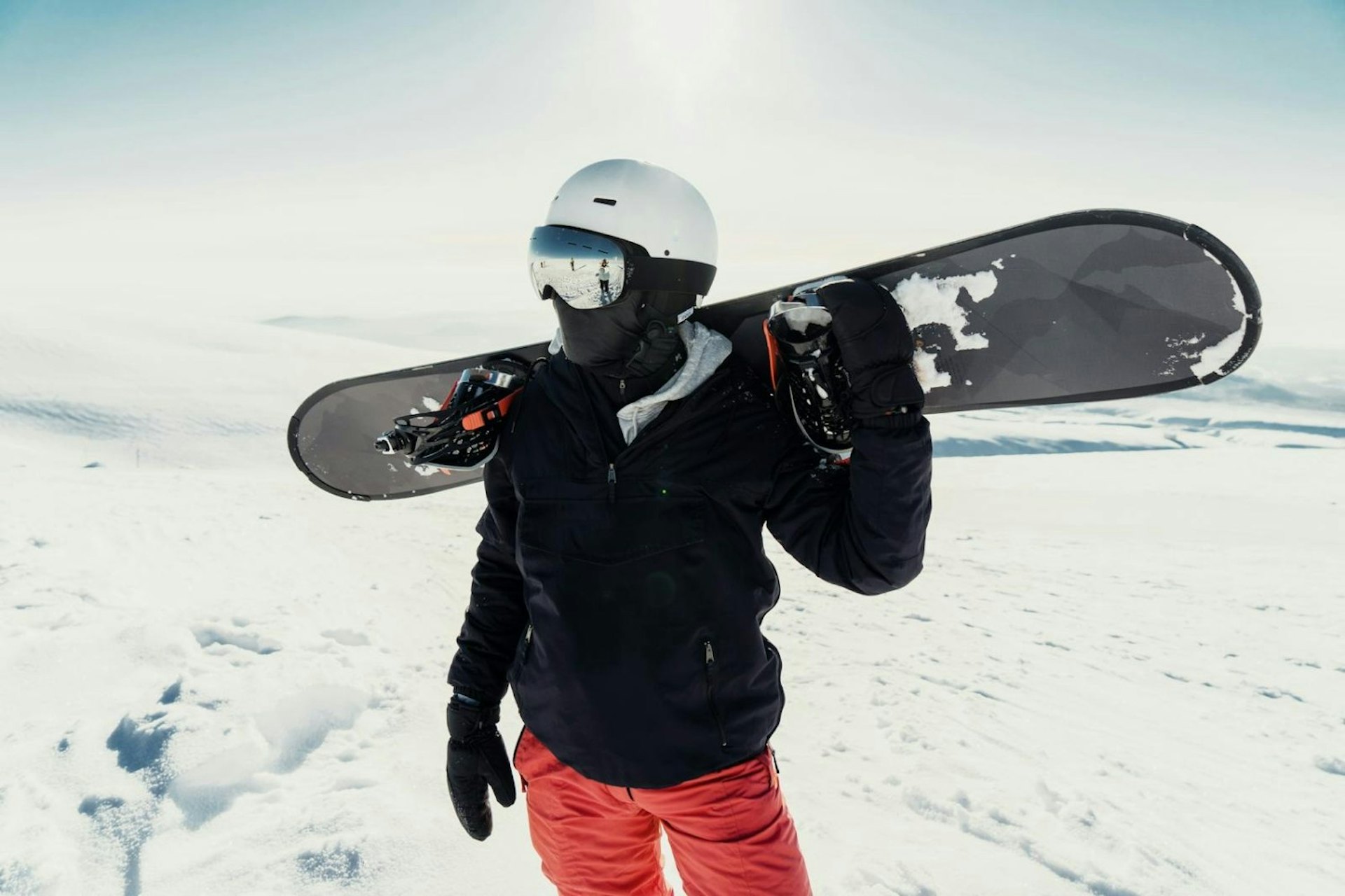 A person stands on a snowy mountain, holding a snowboard, ready for a day of winter sports.