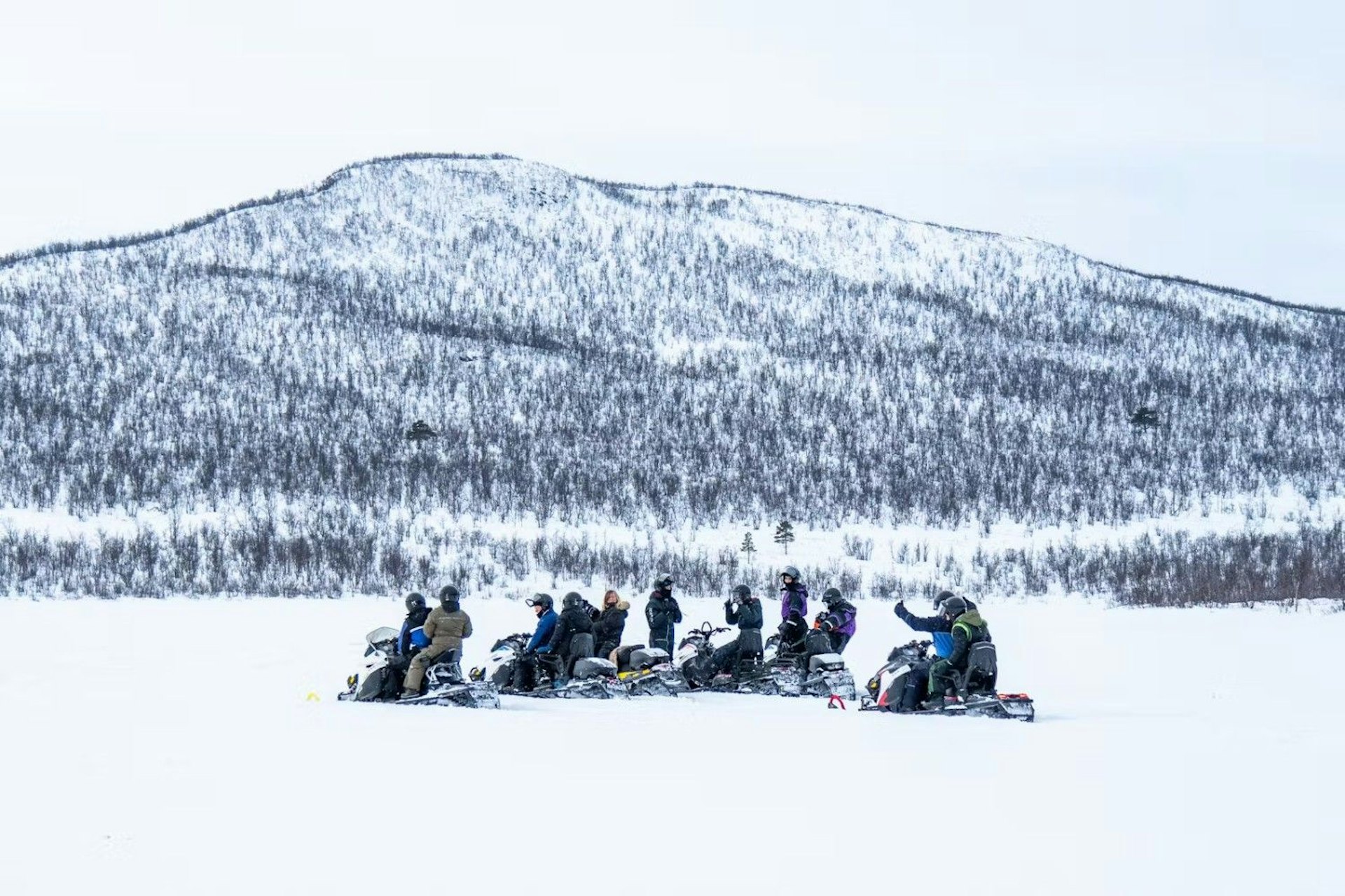 A group of people riding snowmobiles across a snowy landscape, enjoying a winter adventure together.