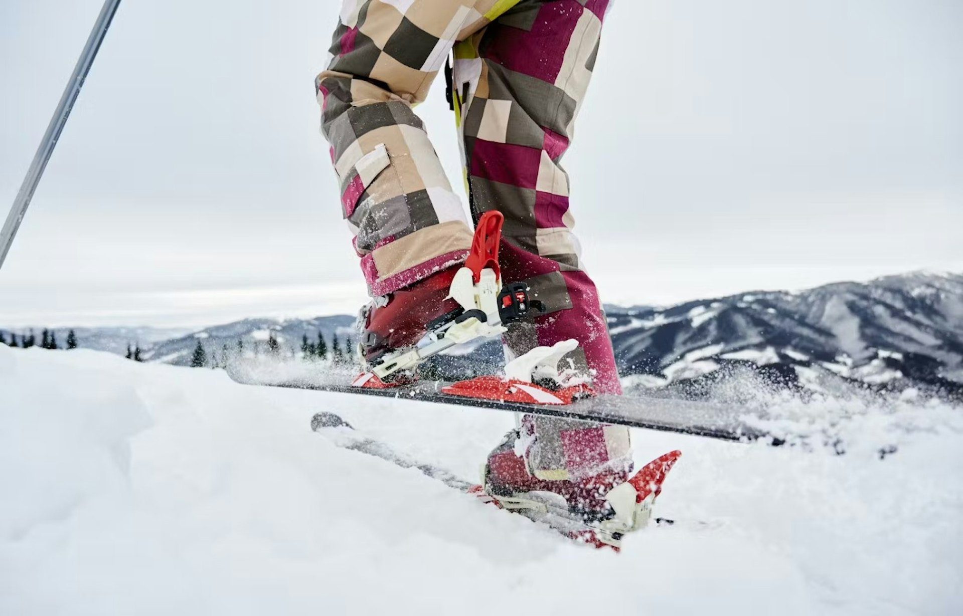 A skier stands on a snowy slope, ready to descend the mountain in a winter landscape.