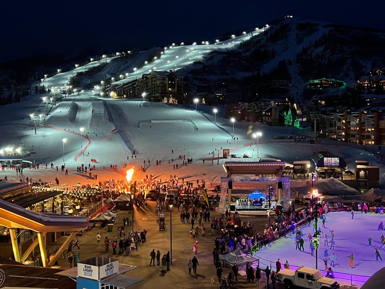 A lively ski resort at night, featuring skiers and visitors enjoying the illuminated slopes and festive atmosphere.