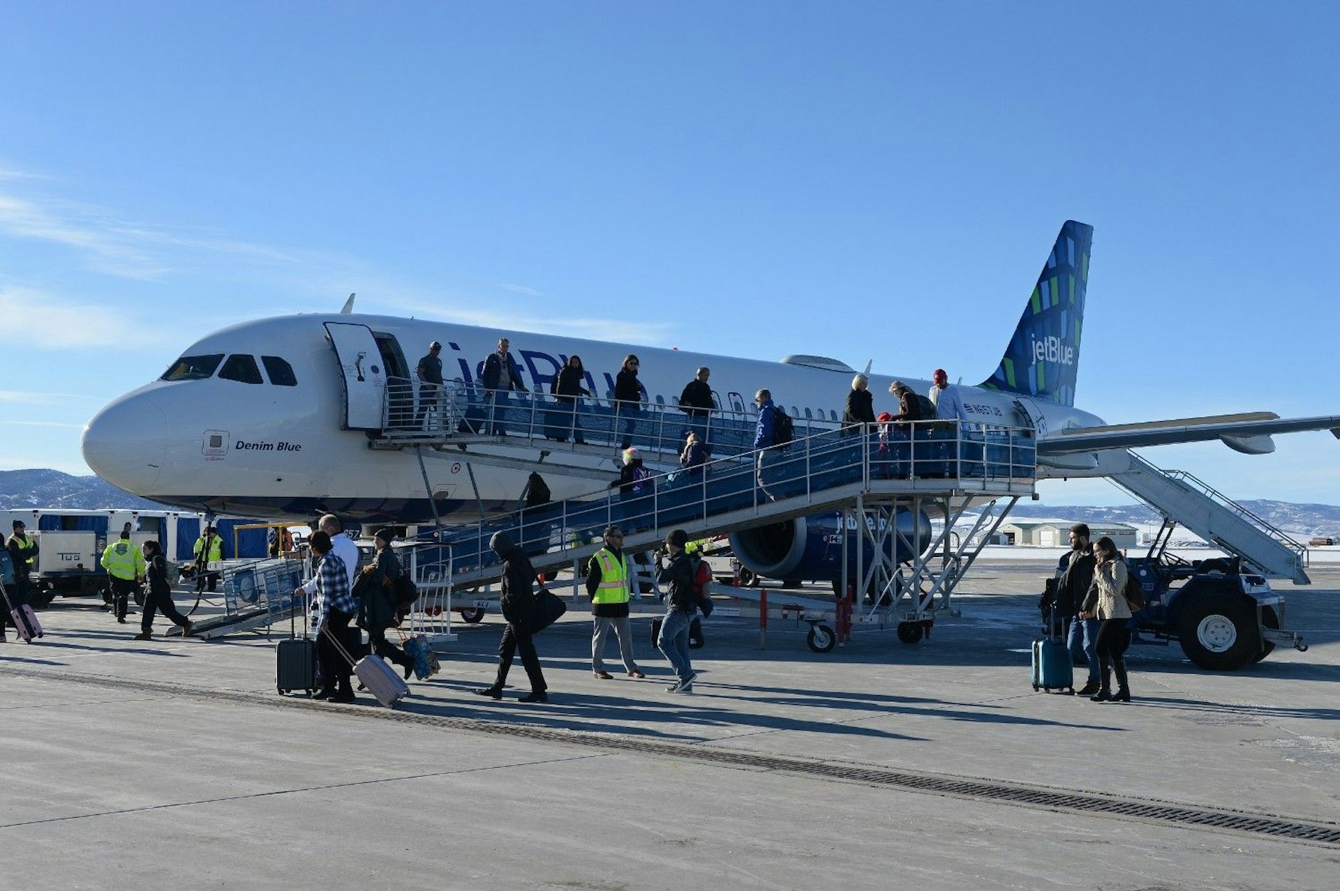 Passengers boarding an airplane at an airport gate, carrying luggage and preparing for their flight.