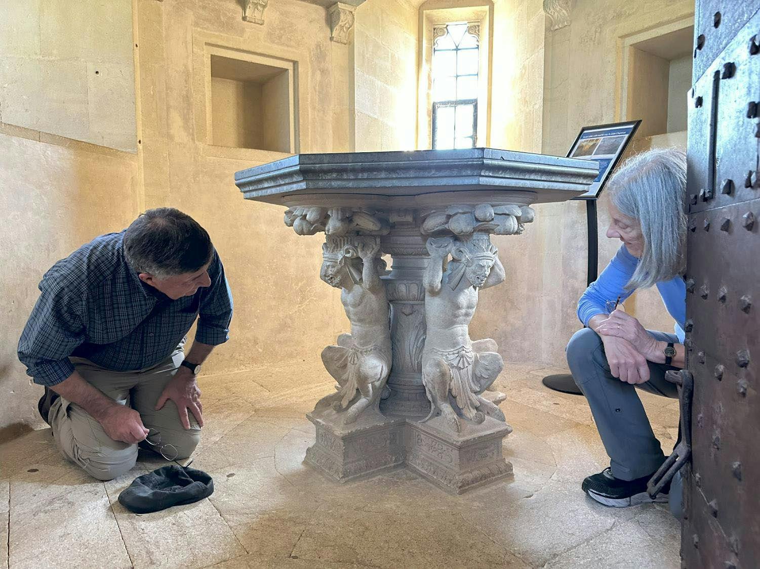 A couple examining an ornate National Trust treasure, a table, Lacock Abbey