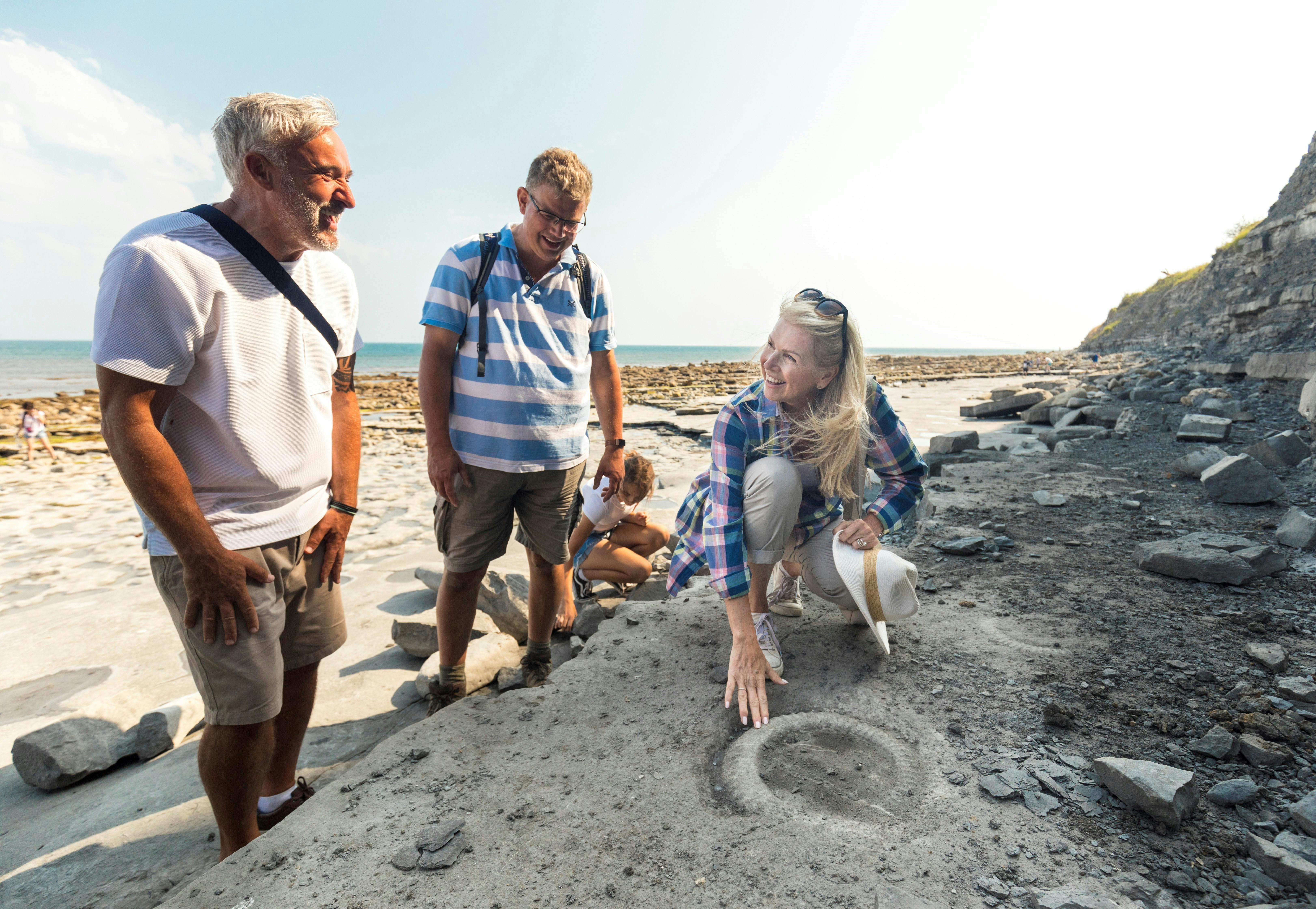 People gathered around an uncovered fossil on Lyme Regis beach