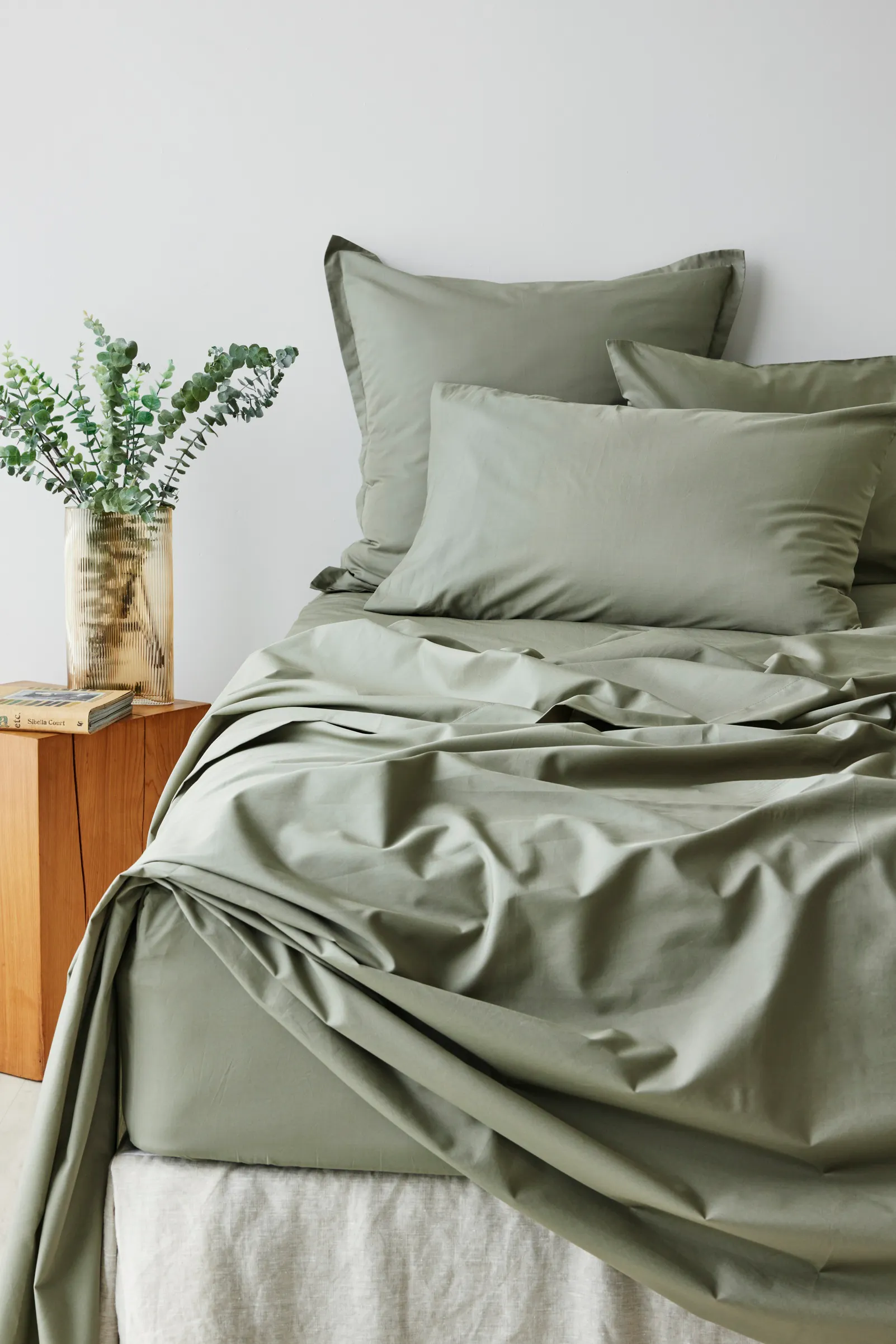 Sage green bedding set with matching pillowcases and sheets styled on a modern bed