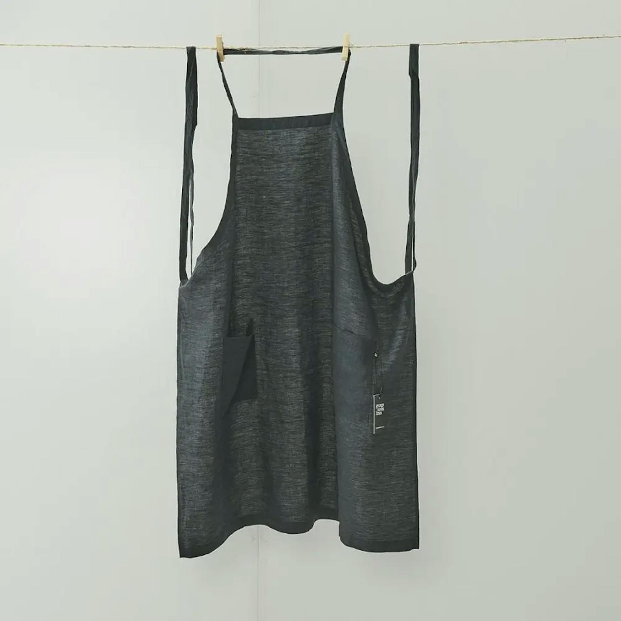 black linen apron hanging on line