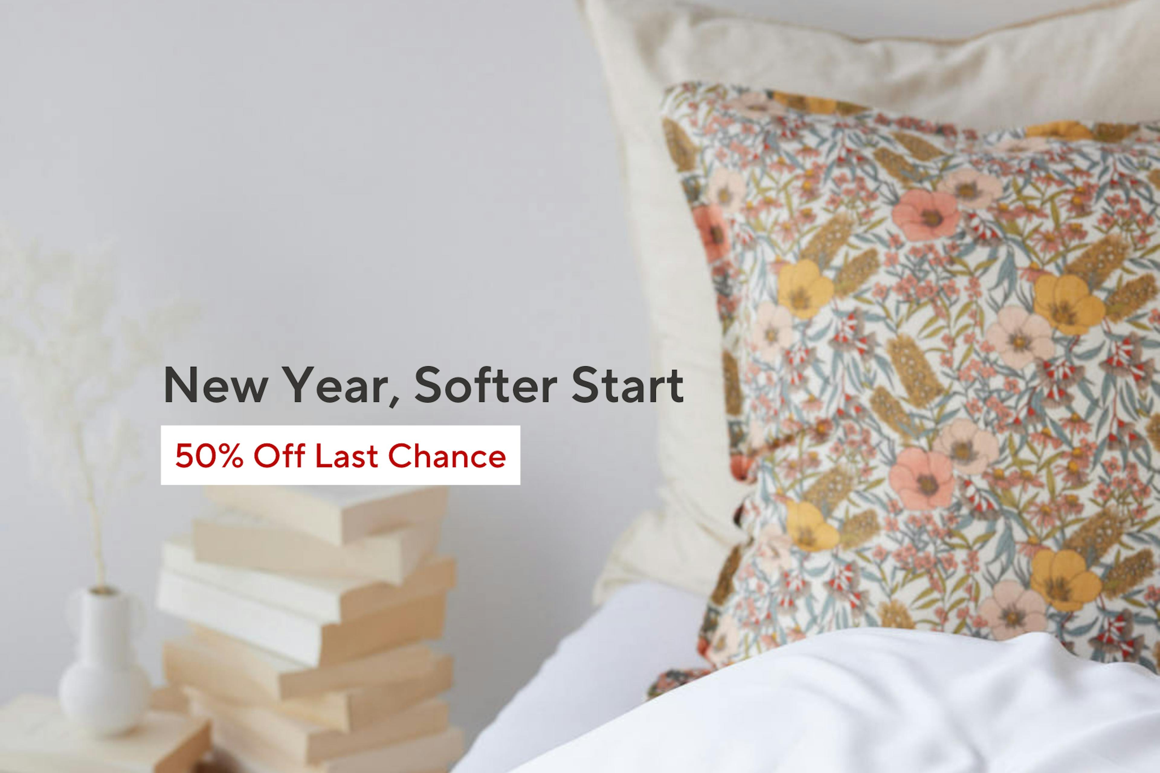 Close up of bed and bed side table, with white sheets, floral pillowcases and books on the side