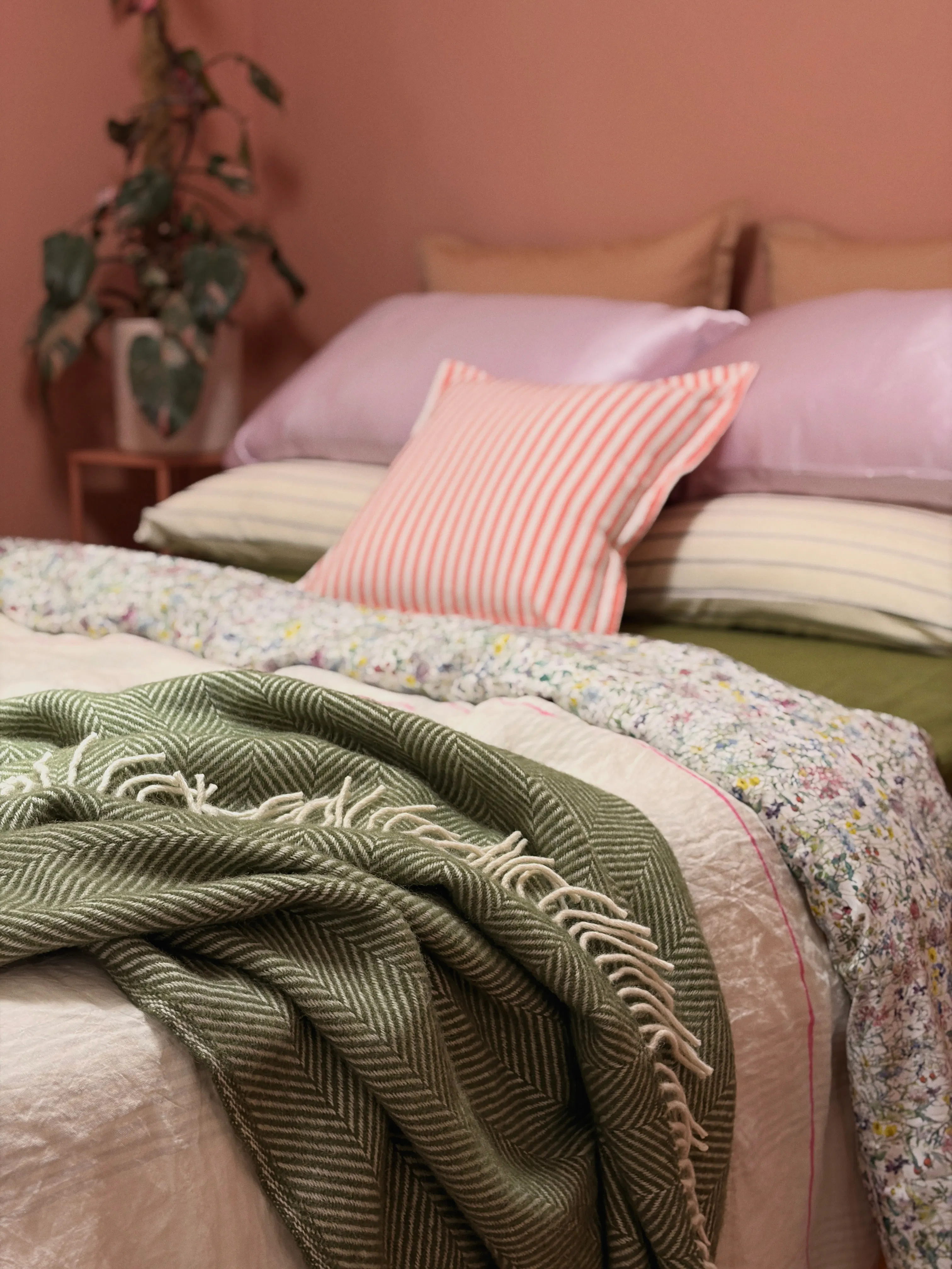 a close up of a bed with many blankets and pillows