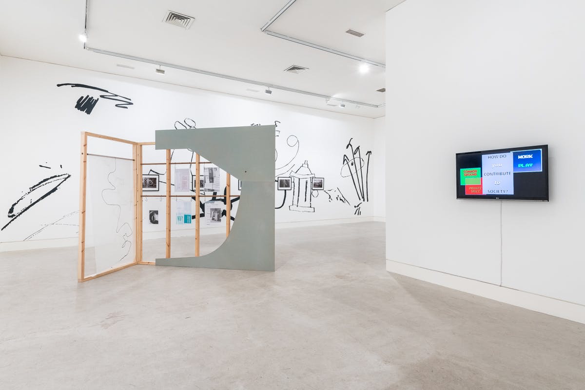 An installation of large sculptural works are situated in a bright gallery space. On the back wall is a large scale black and white painting encompassing over sized doodles. 