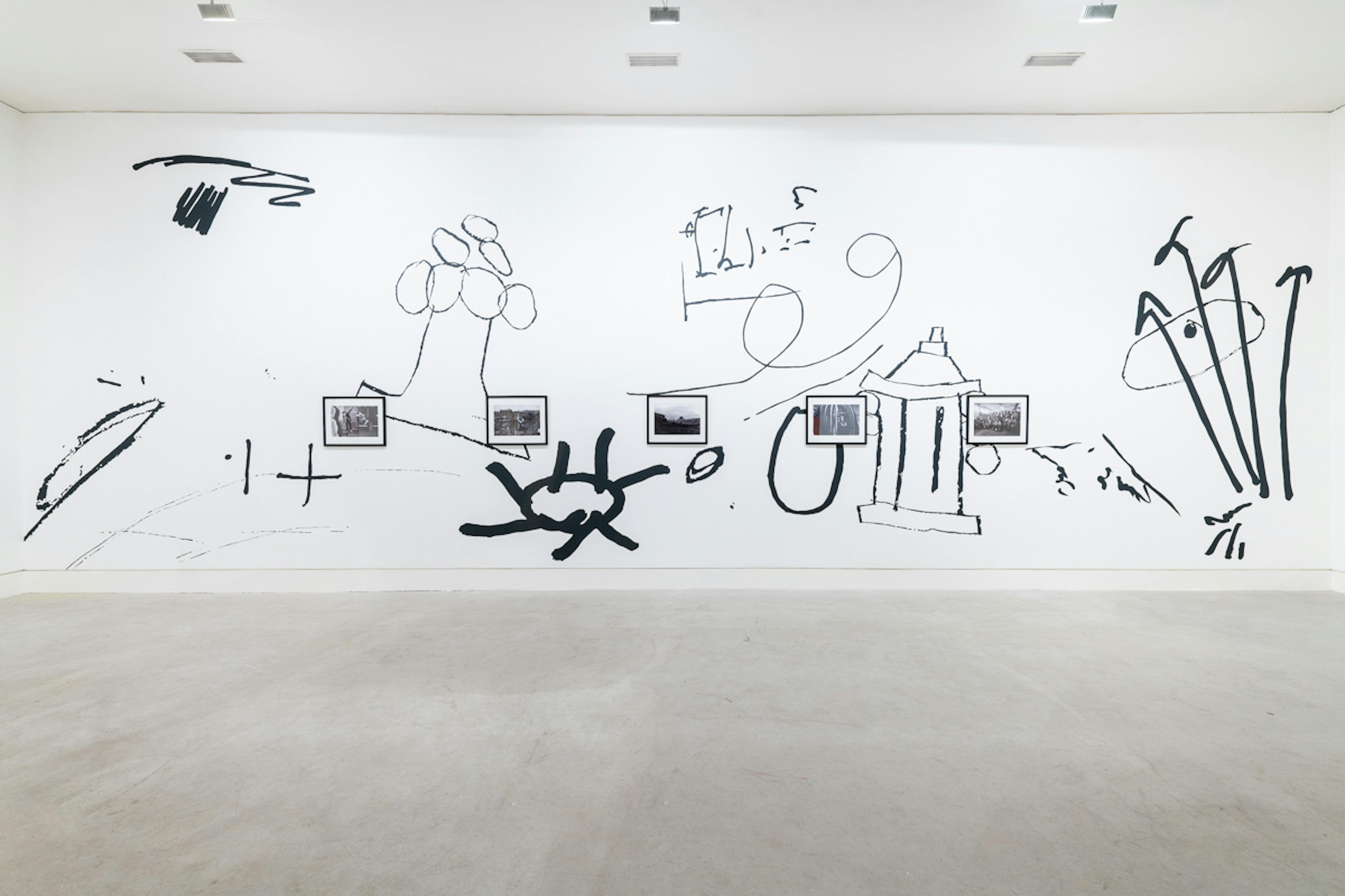 A large scale black and white wall drawing of oversized doodles frames a series of small documentary photographs depicting everyday life in the North-East of England. 