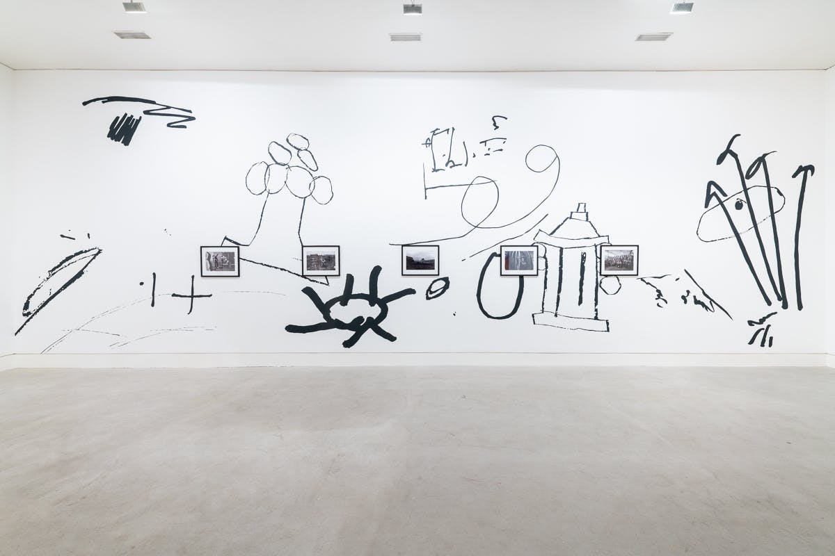 A large scale black and white wall drawing of oversized doodles frames a series of small documentary photographs depicting everyday life in the North-East of England. 