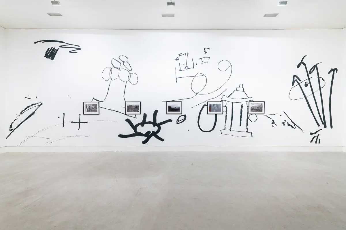 A large scale black and white wall drawing of oversized doodles frames a series of small documentary photographs depicting everyday life in the North-East of England.