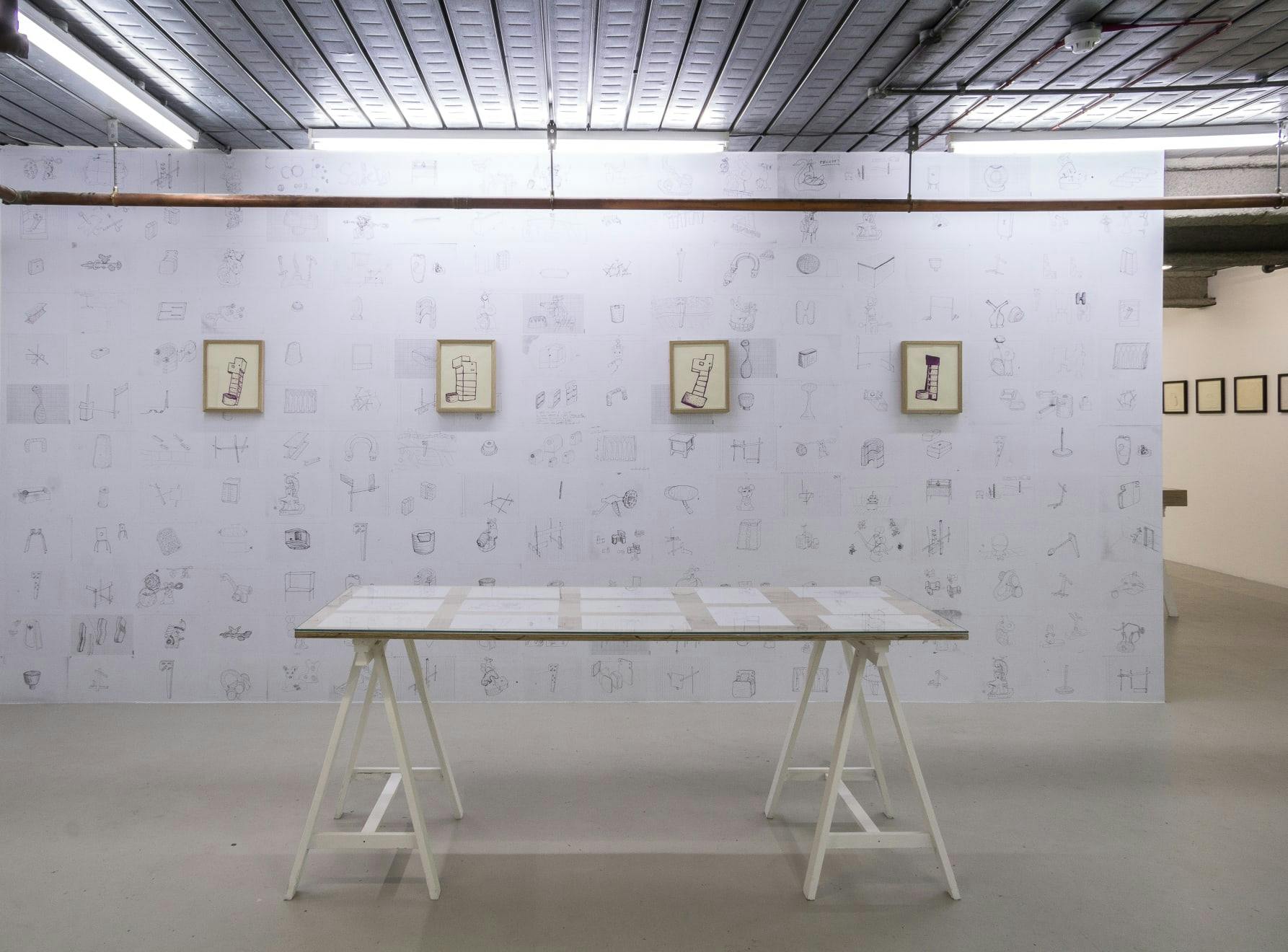 A wall with pasted drawings from the artist's studio frame a series of smaller drawings that express ideas for potential sculptures.