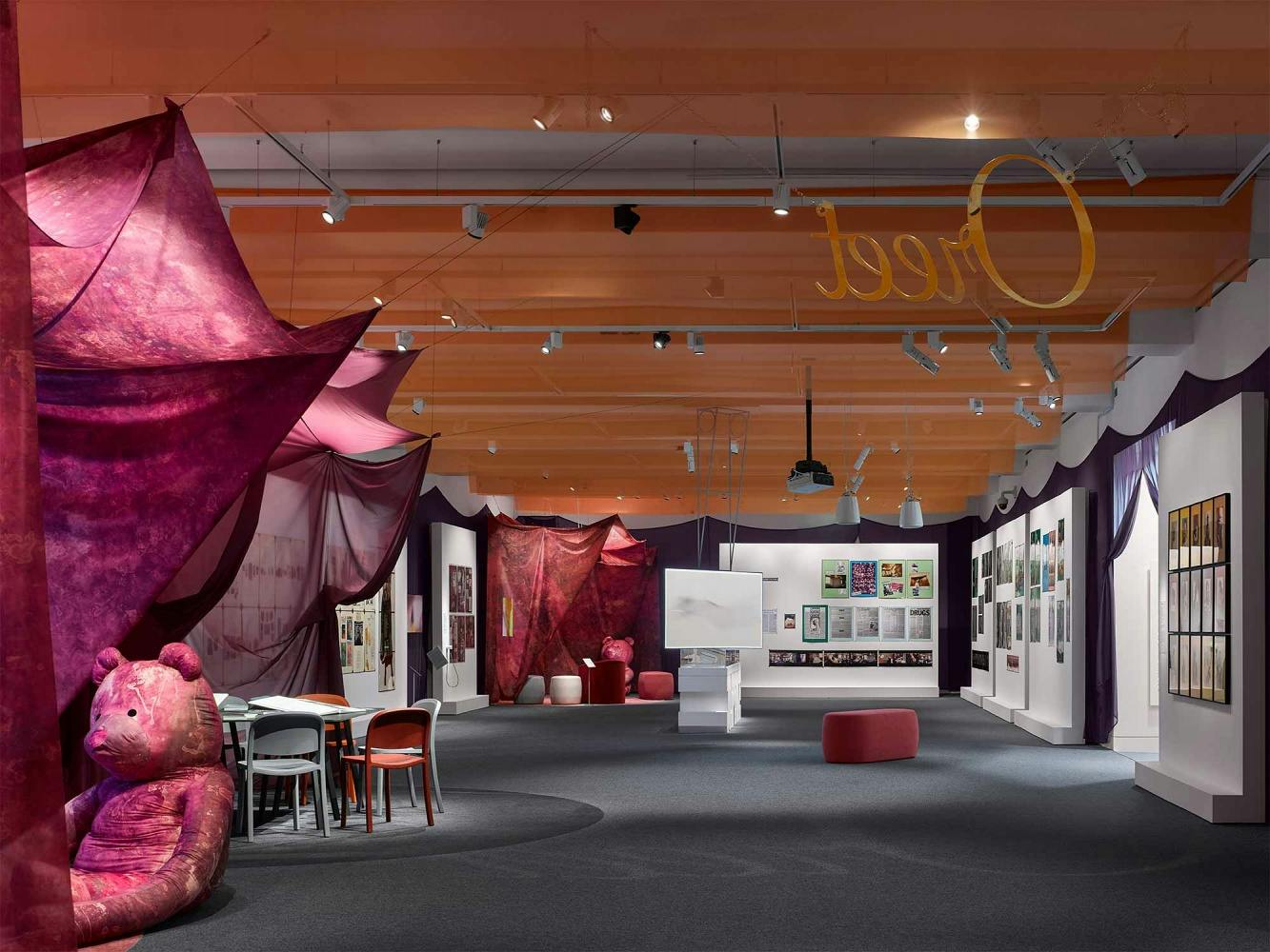 The installation includes photographs on walls of Jo Spence and lots of draped fabric creating a comforting environment. On the ceiling, Oreet Ashery's name is spelled out in gold.