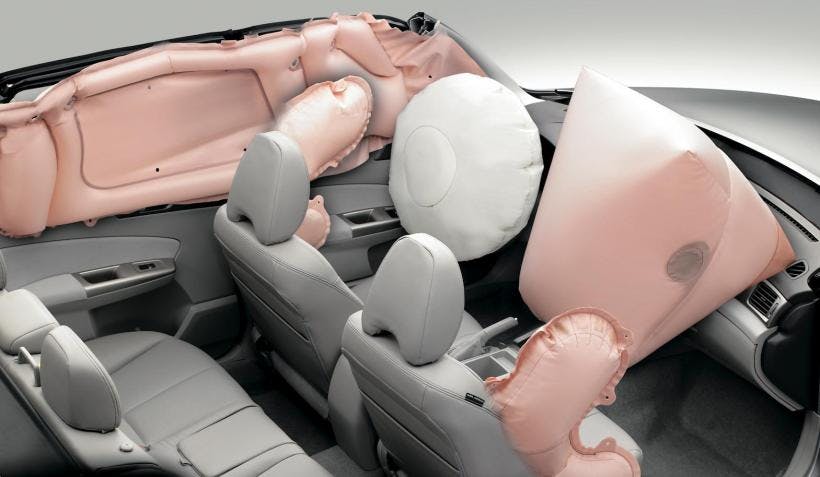A digital rendering of the inside of a sports car. The seats are grey and they are surrounded by inflated pink air bags. 