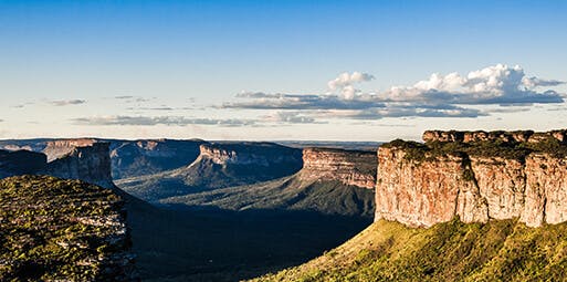 Imagem do Canyon de Lençóis, na Bahia. A foto mostra um dia com tempo aberto, as montanhas iluminadas pelo sol e a vegetação local.