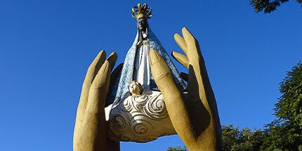 Imagem da Catedral Metropolitana Nossa Senhora Aparecida em Cascavel, Paraná. A foto mostra a escultura de Nossa Senhora em dia ensolarado. 