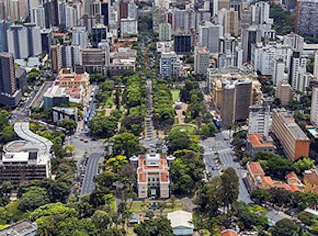 Imagem panorâmica dos prédios da cidade de Belo Horizonte, em Minas Gerais ao pôr do sol. A foto mostra as ruas arborizadas da cidade, suas casas e prédios.