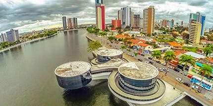 Imagem do Museu de Arte Popular de Campina Grande, na Paraíba. A foto mostra o museu, que tem estrutura arredondada, com prédios ao fundo da imagem.