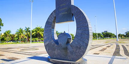 Imagem do Monumento à Bíblia em Palmas, no Tocantins, em dia ensolarado com palmeiras ao fundo.