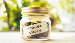 Imagem de pote com tampa contendo moedas. Na parte externa do pote há um papel com a mensagem "Próxima viagem".