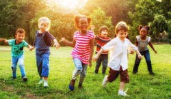 Imagem de diversas crianças correndo no parque ao por do sol.