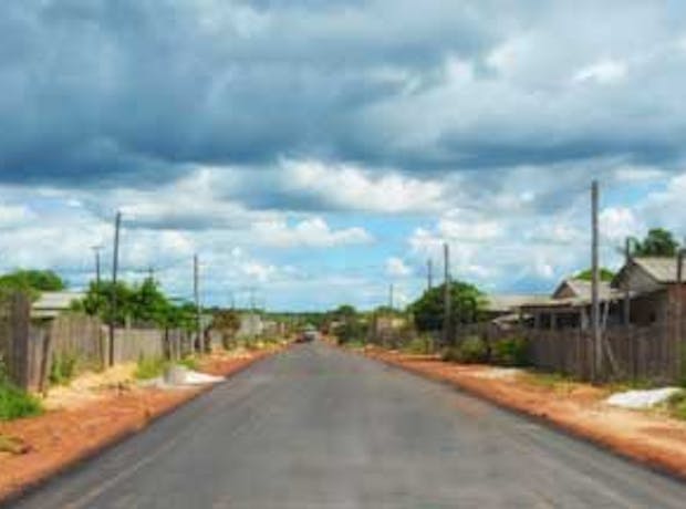 Imagem da cidade de Rorainopolis, em Roraima. A foto mostra uma das ruas da cidade em um dia ensolarado, com casas e árvores de ambos os lados da rua.