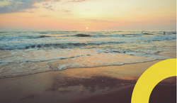 Imagem da orla de uma das praias de São Paulo. A foto mostra o entardecer com céu alaranjado e ondas do mar se quebrando.