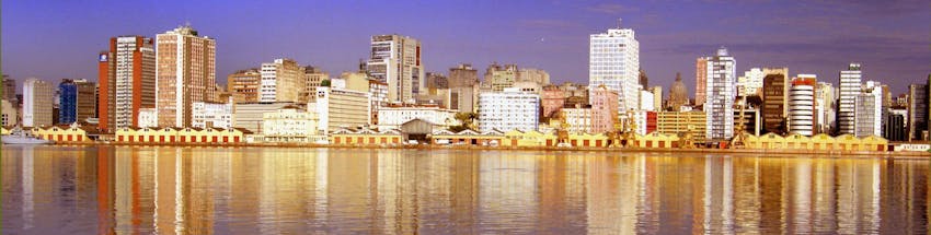 Porto Alegre no entardecer com vista da represa para os prédios na linha do horizonte.