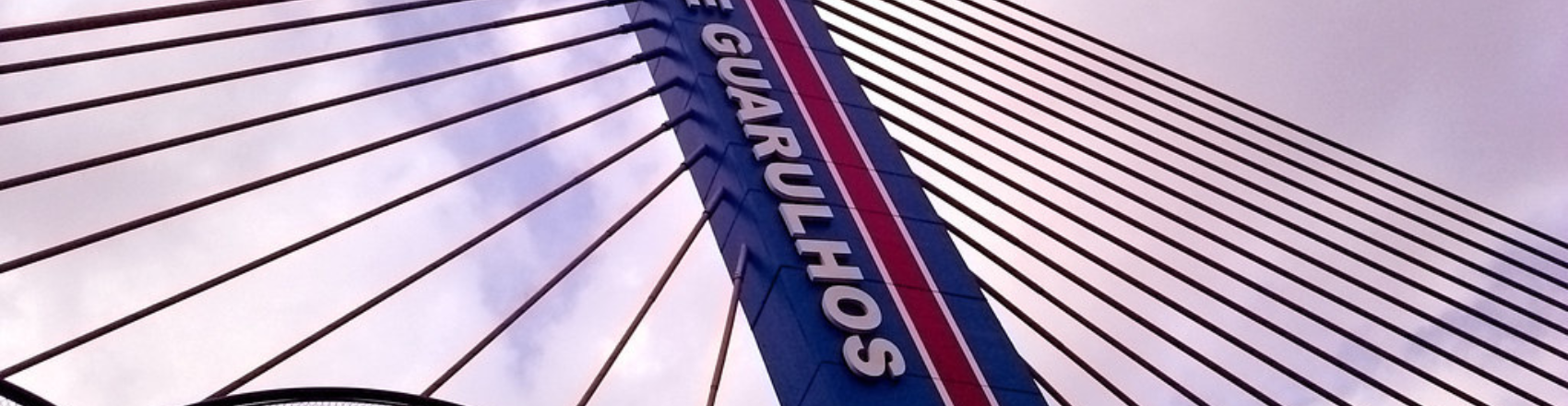 Ponte com cabos de aço e totem azul de Guarulhos.