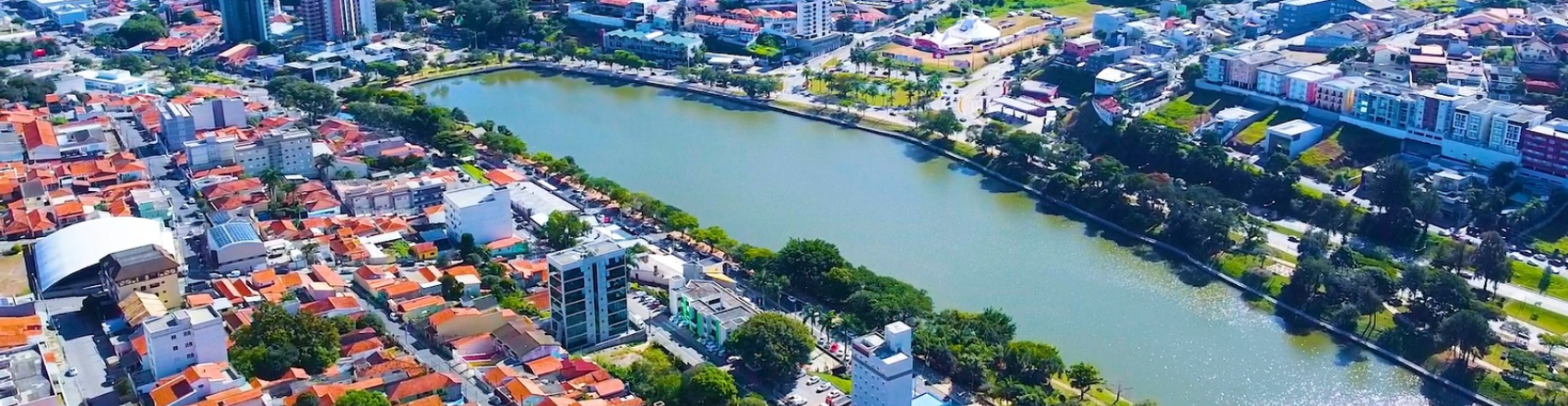 Foto aérea de Bragança Paulista, no interior de São Paulo, com vista dos prédios e casas e um lago em meio à cidade.