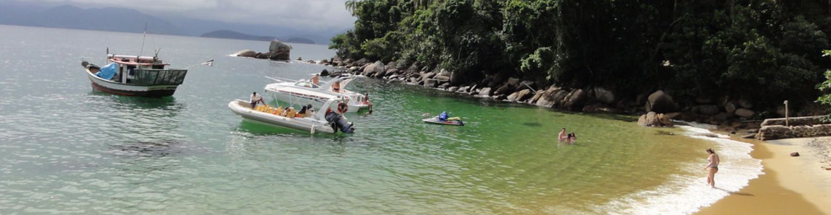Praia Ilha das Couves em Ubatuba, com barcos e banhistas no mar.
