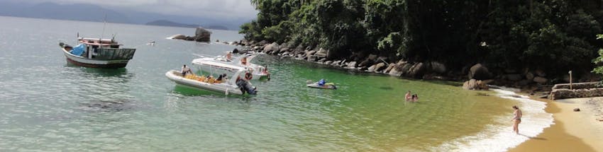 Praia Ilha das Couves em Ubatuba, com barcos e banhistas no mar.