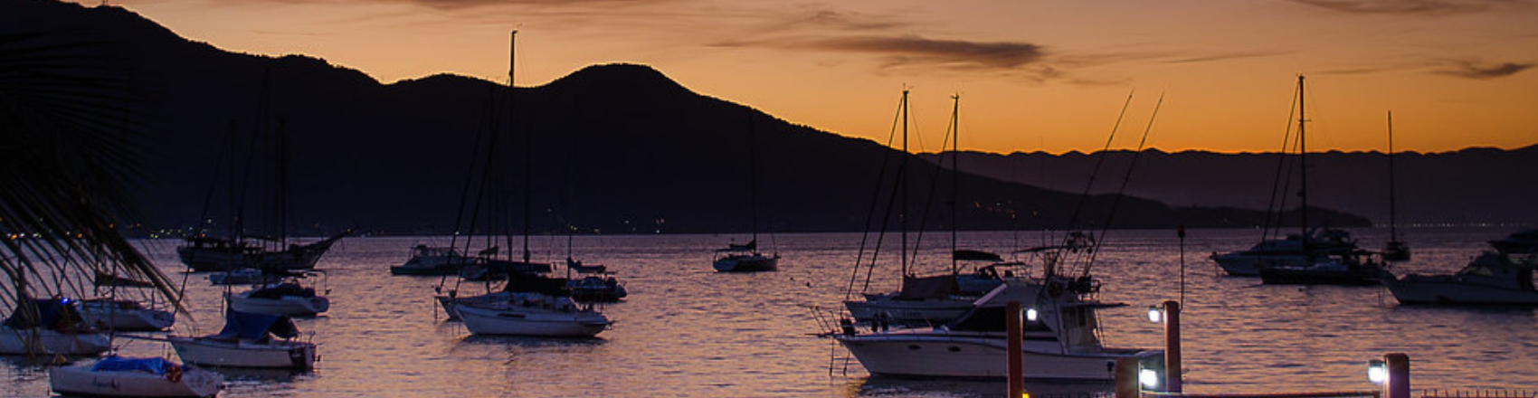 Pôr do Sol no Saco da Capela em Ilhabela com veleiros ancorados na marina.