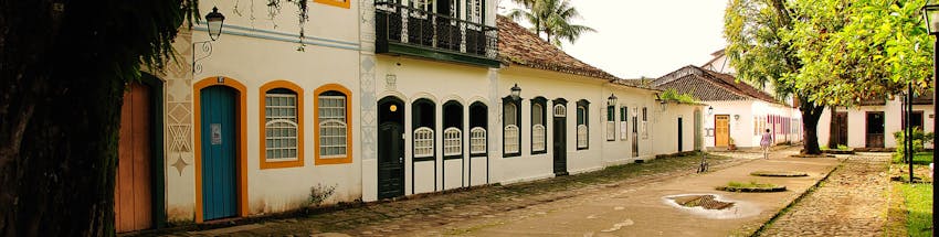 Centro de Paraty com destaque nas construções antigas característica da cidade: casas antigas com portas coloridas e a rua pavimentada com pedras irregulares.