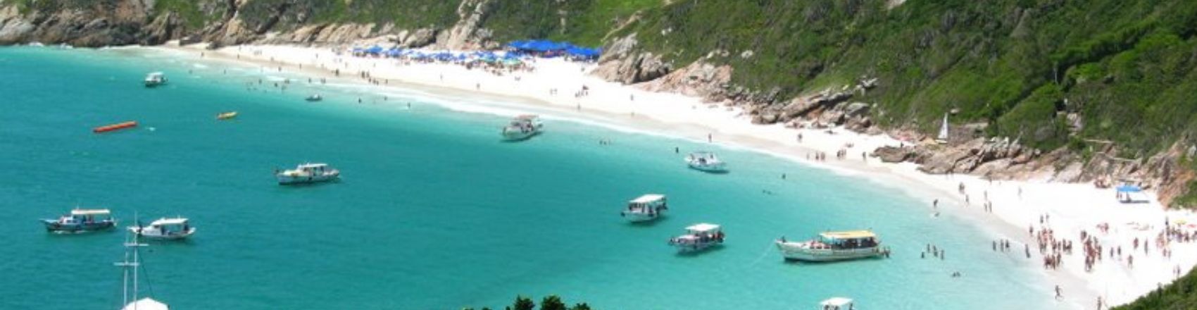Praia de Arraial do Cabo com barcos no mar.