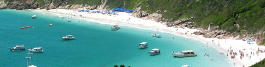 Praia de Arraial do Cabo com barcos no mar.