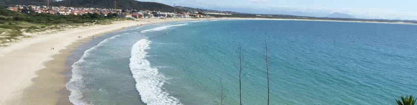 Praia de Cabo Frio no Rio de Janeiro. A costa da areia é clara e o mar é calmo com poucas ondas.
