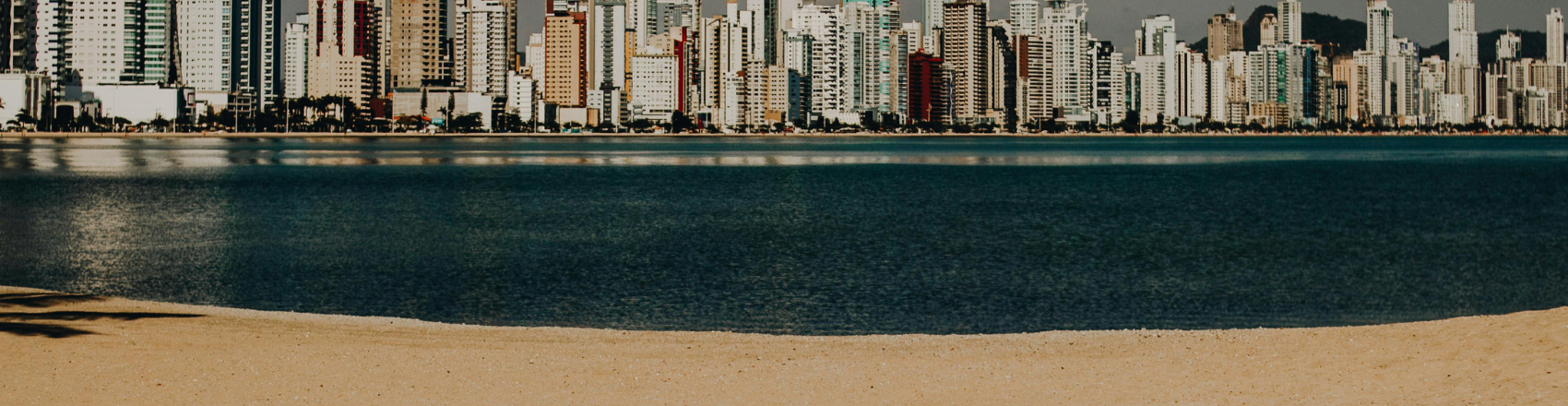 Praia de Balneário Camboriú com vista dos prédios à beira-mar no horizonte.