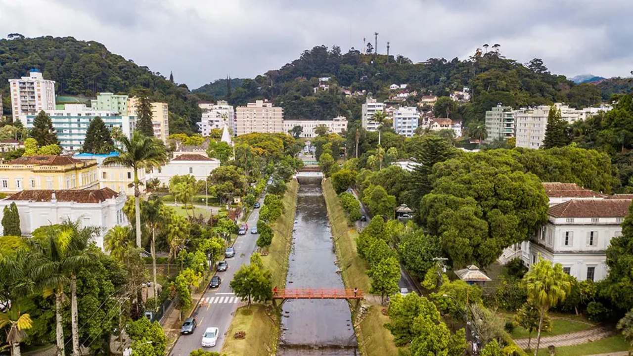 Rua no centro de Petrópolis, no Rio de Janeiro, com prédios, árvores, ruas e céu azul claro.