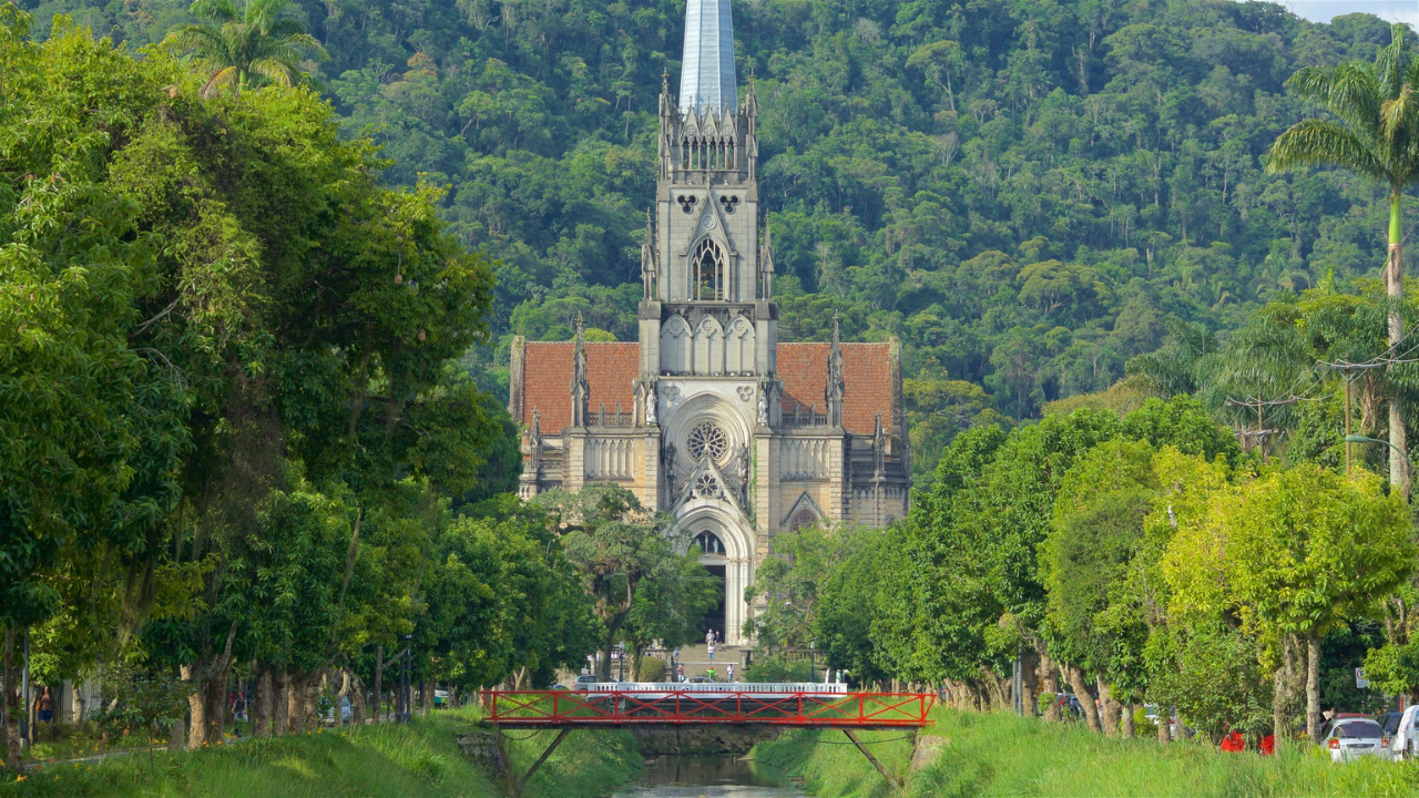 Catedral de São Pedro de Alcântara em Petrópolis, no Rio de Janeiro, de arquitetura neogótica e arcos pontudos, com uma bela rosácea no centro. Nas duas margens do pequeno corpo d'água que fica em frente à catedral, há árvores. 