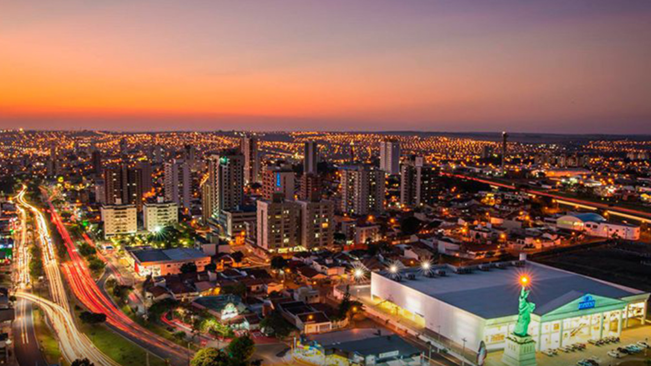 Bauru, em São Paulo, vista de cima durante o pôr do sol, com prédios e ruas iluminando a cidade.
