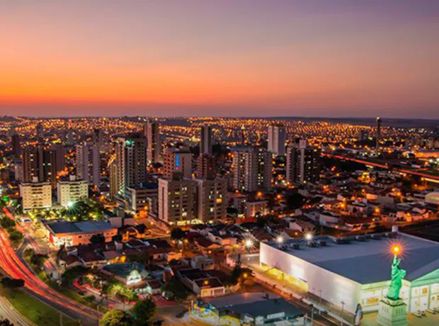 Bauru, em São Paulo, vista de cima durante o pôr do sol, com prédios e ruas iluminando a cidade.